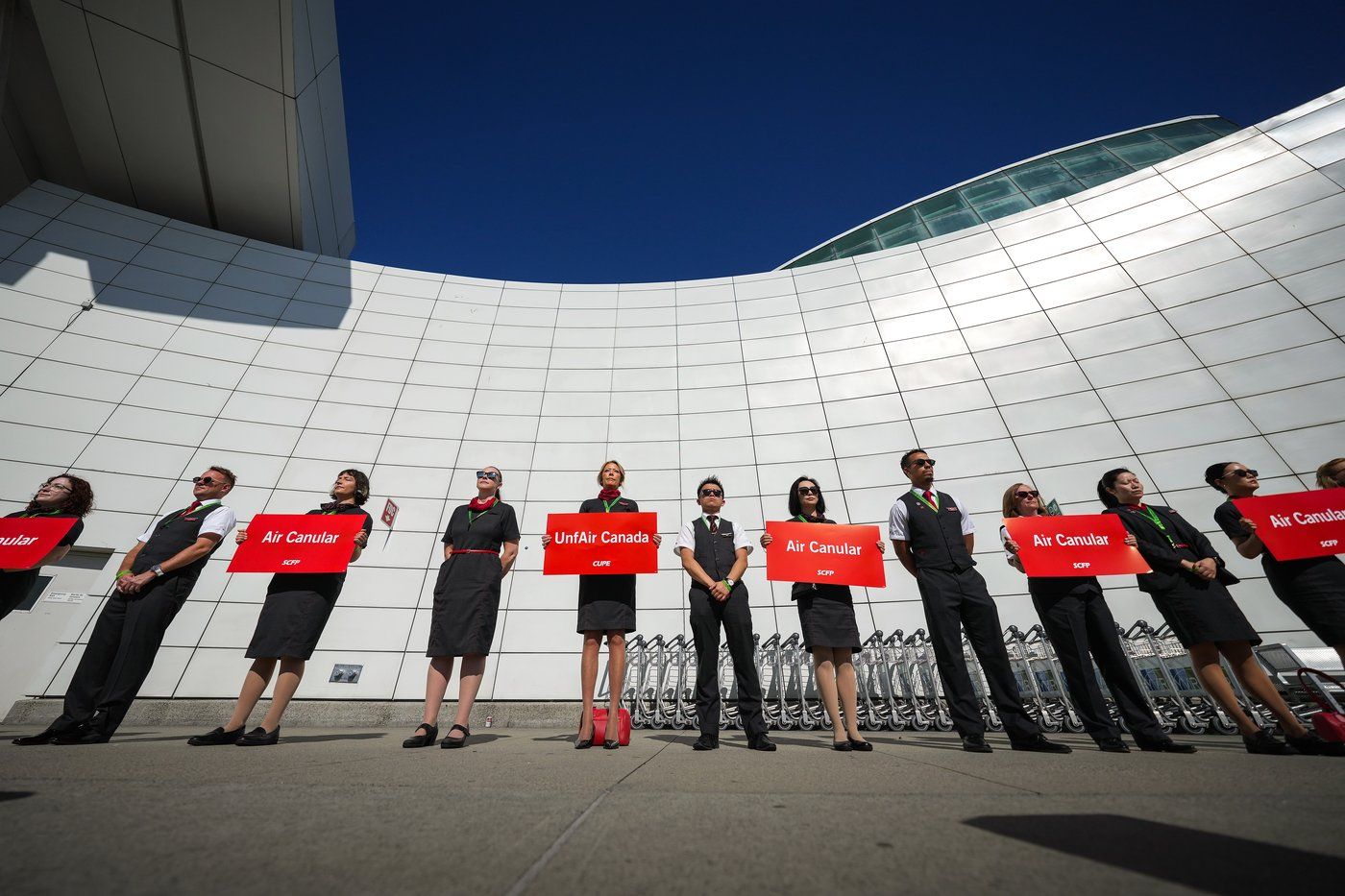 Air Canada flight attendants stand during a silent protest at Vancouver International Airport on a national day of action, as labour negotiations between the Canadian Union of Public Employees and the airline continue, in Richmond, B.C., on Monday, Aug. 11, 2025. THE CANADIAN PRESS/Darryl Dyck